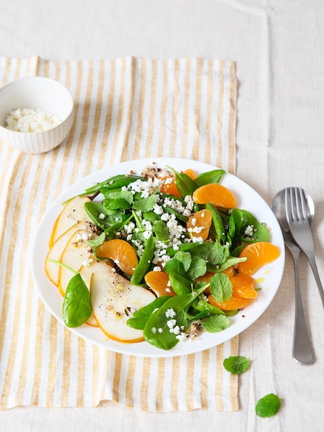 Ensalada de espinacas y quinoa con peras, naranjas y ricotta. Preparación de comidas saludables. Platos a base de plantas. Vida verde. Receta vegana. Peinado de alimentos. Cocina vegetariana. Alimentación saludable. Concepto de comida para bajar de peso.