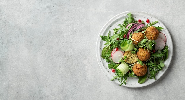 Ensalada de falafel y verduras en un plato de cerámica blanca sobre una superficie de hormigón copia espacio concepto de comida vegetariana