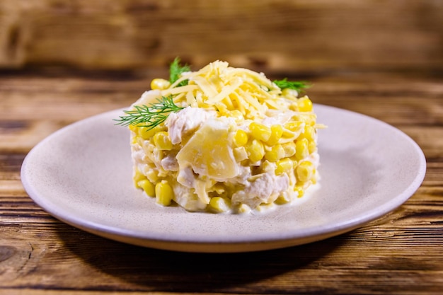 Ensalada festiva con pechuga de pollo, piña enlatada, queso, maíz dulce y mayonesa sobre mesa de madera rústica