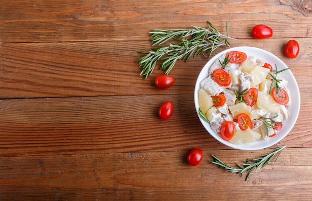 Ensalada del filete del pollo con los tomates del romero, de la piña y de cereza en fondo de madera marrón.