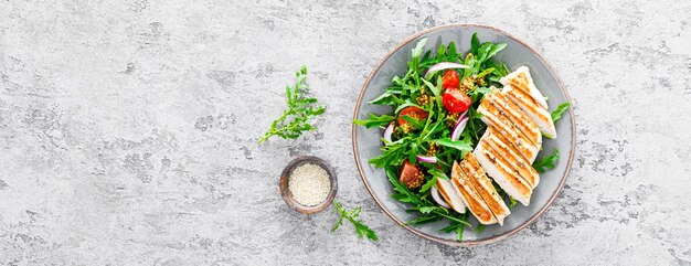 Ensalada de filete de pollo con verduras frescas y rúcula Ensalada de verduras frescas de rúcula tomates cebolla y pechuga de pollo a la plancha Banner