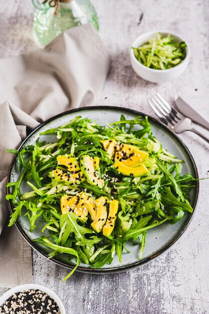 Ensalada de fitness dietética de aguacate de pepino y rúcula en un plato en la mesa vista vertical