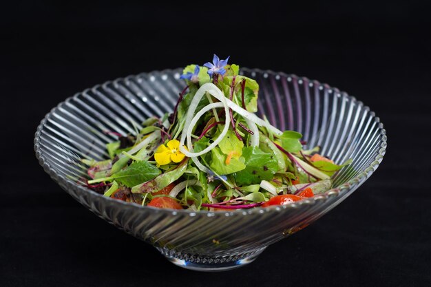 Una ensalada con flores azules y una flor amarilla encima