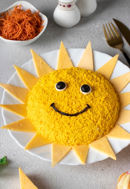 Ensalada en forma de sol con huevos de gallina zanahorias y queso sobre fondo gris claro Idea culinaria para fiesta infantil