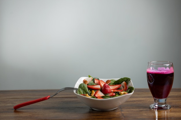 Ensalada de fresas y espinacas con jugo de remolacha en mesa de madera