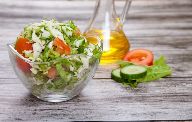 Ensalada fresca y aceite vegetal en una mesa de madera