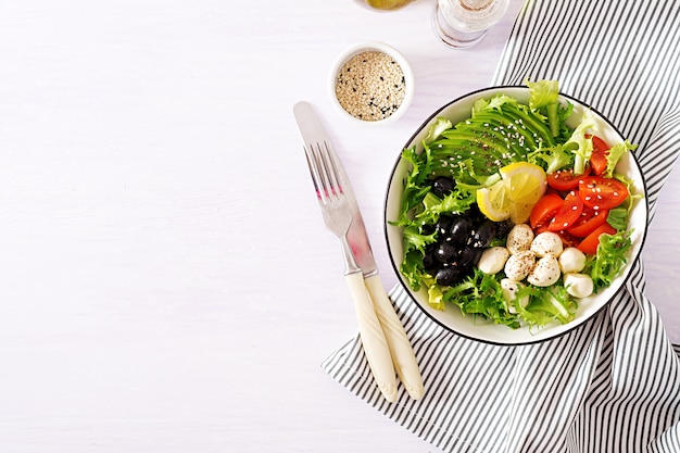 Ensalada fresca con aguacate, tomate, aceitunas y mozzarella en un bol.