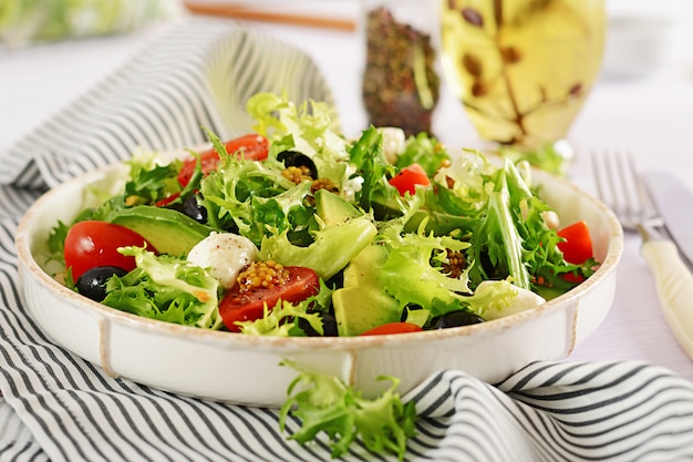 Ensalada fresca con aguacate, tomate, aceitunas y mozzarella en un tazón.