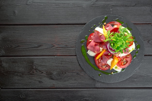 Ensalada fresca de caqui con rúcula, jamón de Parma, aceite de oliva y hierbas. otoño, invierno comida sana