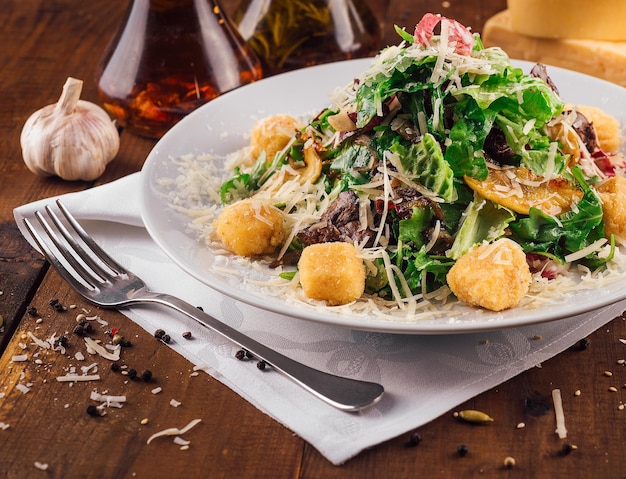 Una ensalada fresca con carne y croutons que se sirve en una mesa de madera