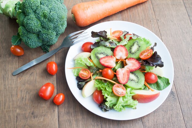 Ensalada fresca con fresas, kiwi, tomates y manzanas en plato blanco