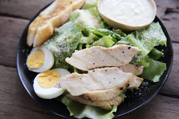 Ensalada fresca con pechuga de pollo sobre fondo de madera