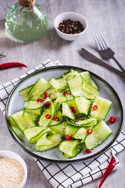 Foto ensalada fresca de pepinos pimiento rojo picante y semillas de sésamo en una vista vertical de la placa