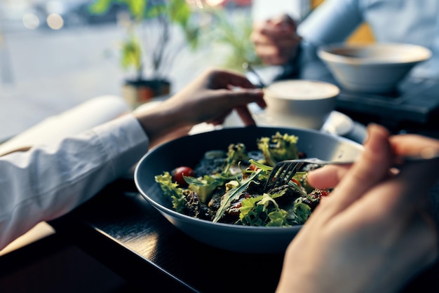 Foto ensalada fresca en un plato, comida deliciosa, dieta, tenedor en mano, manos femeninas, café