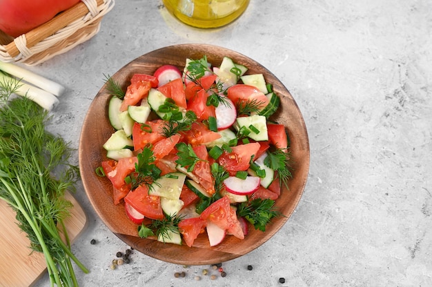 Ensalada fresca de primavera con tomate pepino rábano cebolla verde perejil eneldo y aceite de oliva closeup