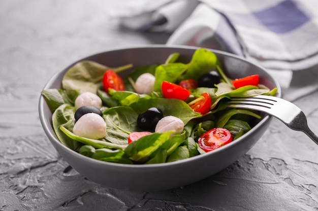 Foto ensalada fresca con queso mozzarella, tomate, primer plano de espinacas. comida sana.