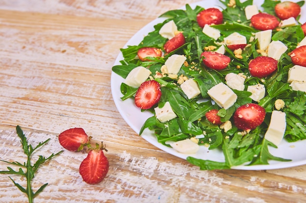 Ensalada fresca con rúcula, fresas, queso feta y nueces.