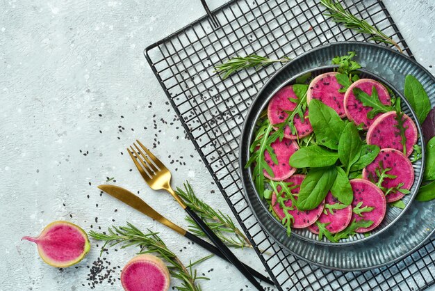 Foto ensalada fresca y saludable espinacas rábano sandía sésamo negro y aceite de oliva comida saludable vista superior sobre un fondo de piedra