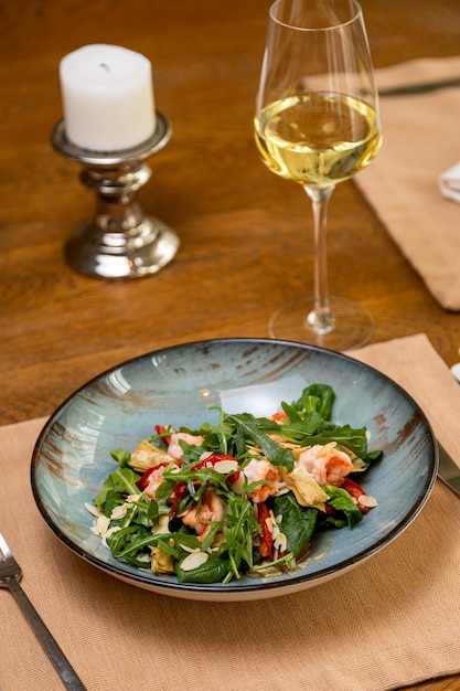 Ensalada fresca servida con una copa de vino servido en mesa