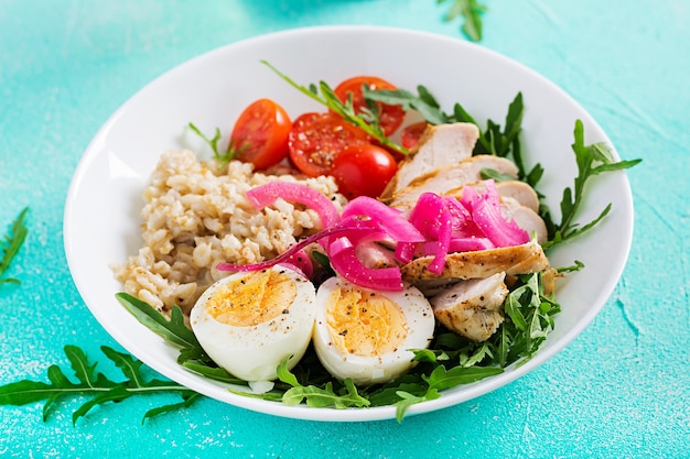 Ensalada fresca. tazón de desayuno con avena, filete de pollo, tomate, cebolla morada y huevo cocido. comida sana. cuenco de buda vegetariano.