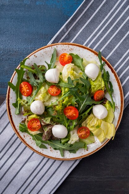 Ensalada fresca con tomate, rúcula, lechuga y mozzarella en un plato. Concepto de comida sana y dietética. Vista superior.