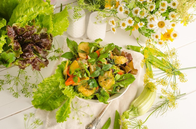 Ensalada fresca de verano con zanahorias de calabacín y hierbas en un bol sobre una mesa de madera clara