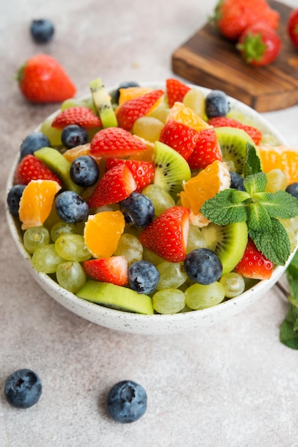 Foto ensalada de frutas de arándanos, fresas, uvas y kiwi en un plato, enfoque selectivo