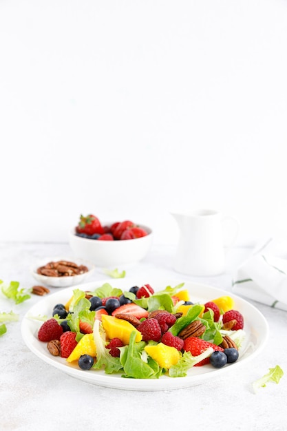 Ensalada de frutas y bayas con fresa, arándano, frambuesa, mango y nueces pecanas Dieta alimentaria saludable