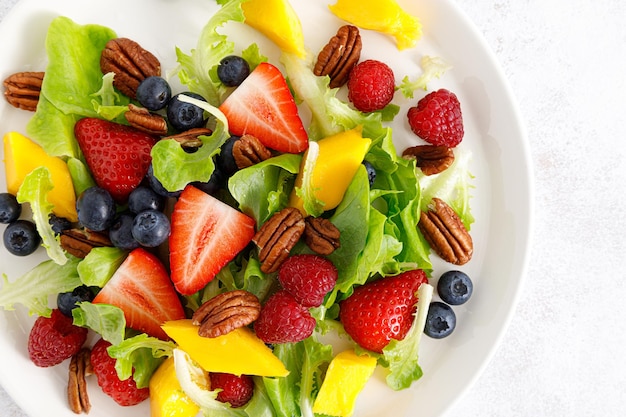 Ensalada de frutas y bayas con fresa, arándano, frambuesa, mango y nueces pecanas Dieta de alimentos saludables Vista superior