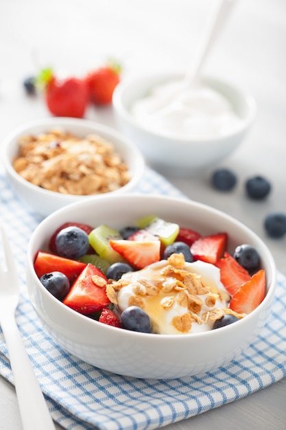 Ensalada de frutas y bayas con yogurt y granola para un desayuno saludable