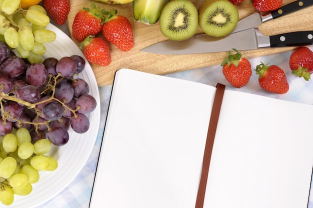 Ensalada de frutas con libro de recetas en blanco