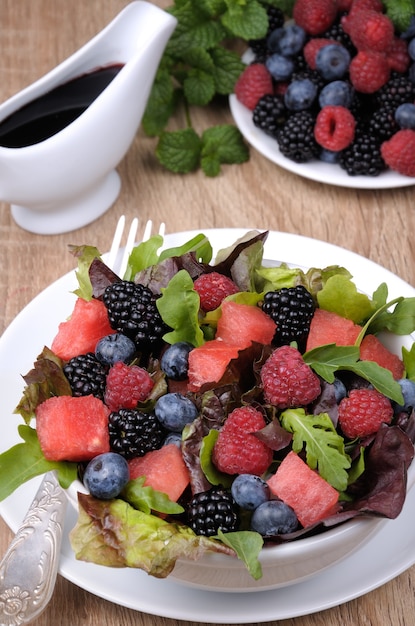 Ensalada de frutas con rodajas de sandía, mora, frambuesa, arándano y mezcla de hojas verdes