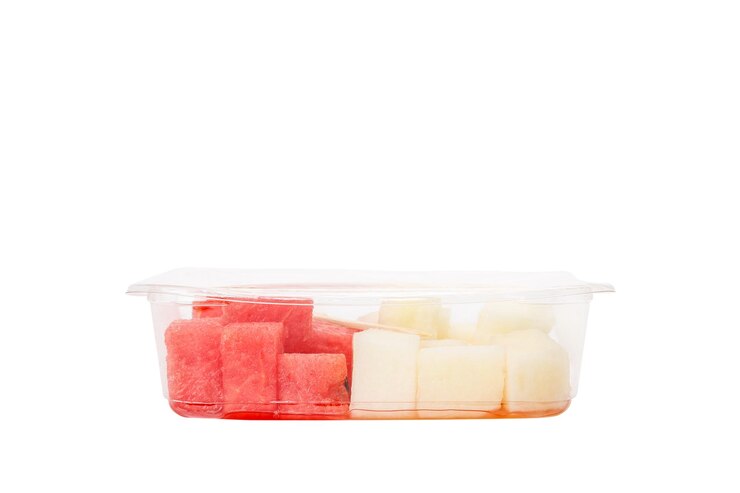 Ensalada de frutas con sandía y melón en un recipiente de plástico sobre un fondo blanco