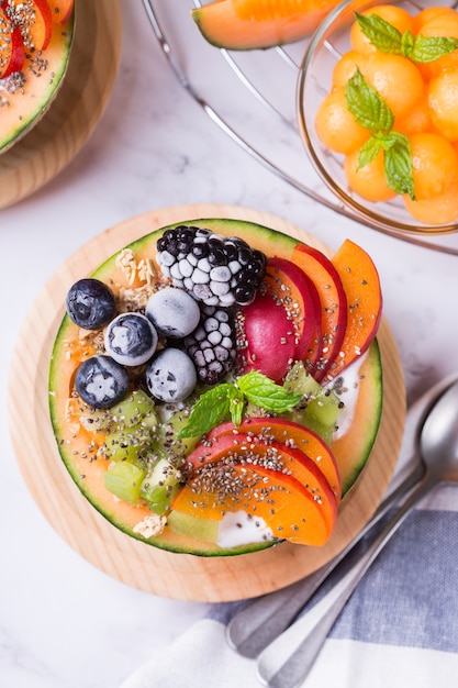 Ensalada de frutas con yogur en tazón de melón melón tallado en la mesa