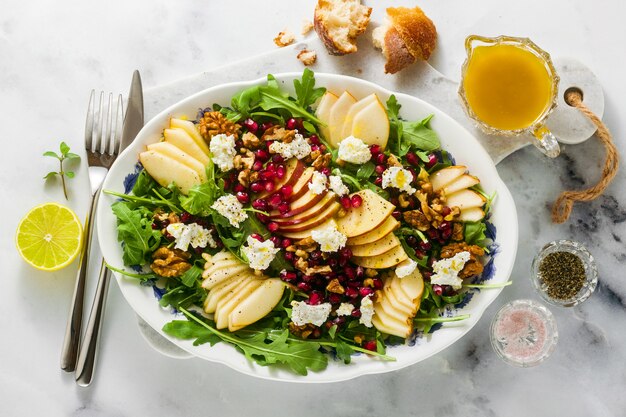 Ensalada de granada y pera verde con aderezo de jengibre sobre mármol blanco. desayuno o almuerzo saludable