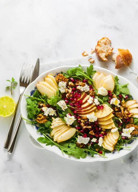 Ensalada de granada y pera verde con aderezo de jengibre sobre mármol blanco. desayuno o almuerzo saludable