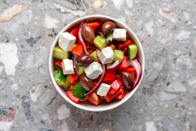 Ensalada griega dietética con tomates feta verdes sobre un fondo de piedra gris vista superior Almuerzo saludable