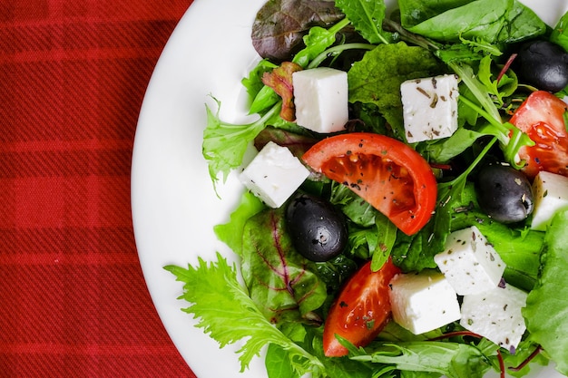 Ensalada griega fresca en plato blanco sobre fondo rojo. primer plano y vista superior.