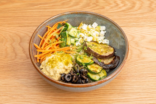 Ensalada griega con hummus de garbanzos queso feta picado pepino crudo calabacín sin hueso aceitunas negras zanahoria rallada berenjena frita y aceite de oliva