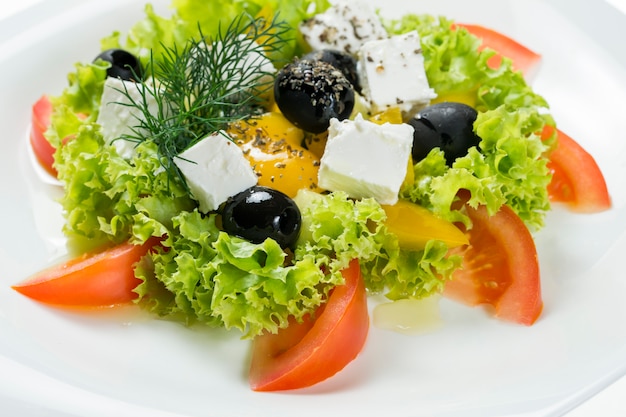 Ensalada griega en plato en blanco