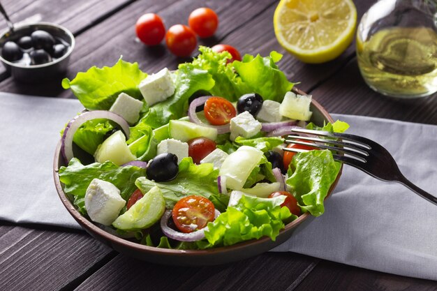 Ensalada griega en un plato sobre un fondo de madera oscura. Comida vegetariana saludable.