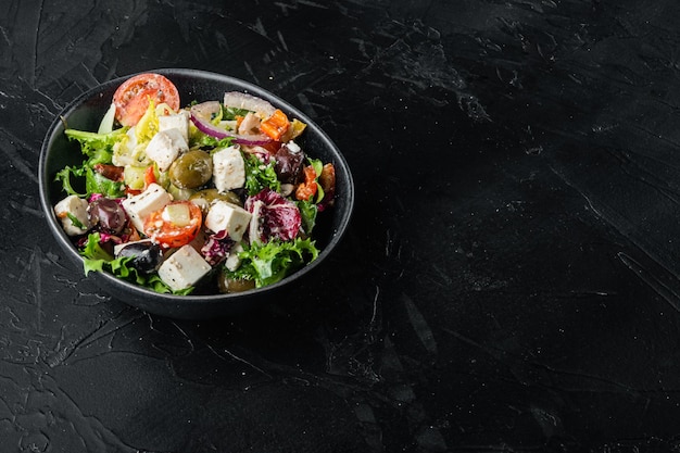 Ensalada griega con queso feta y aceitunas frescas orgánicas sobre fondo negro con espacio para copiar texto