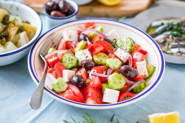 Ensalada griega con queso feta, aceitunas, tomate cherry, pimentón, pepino y cebolla roja, vegetariana saludable, dieta mediterránea, alimentos bajos en calorías, comer vista superior de fondo de piedra blanca