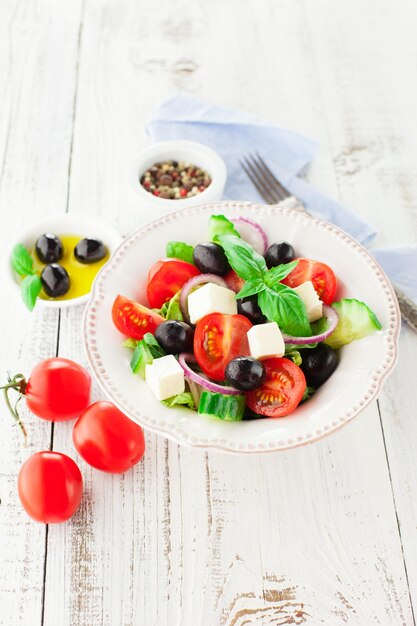 Foto ensalada griega con queso feta verduras frescas y aceitunas sobre un fondo blanco rústico enfoque selectivo