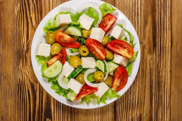 Ensalada griega con queso feta de verduras frescas y aceitunas verdes en la mesa de madera Vista superior