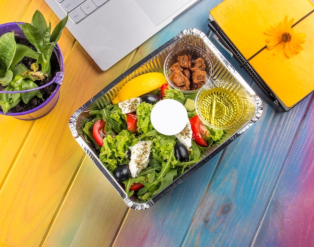 Ensalada griega en recipiente sobre fondo de madera de color Dieta para llevar y comida saludable