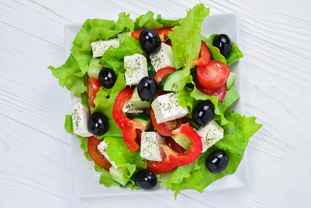 Ensalada griega sobre madera blanca