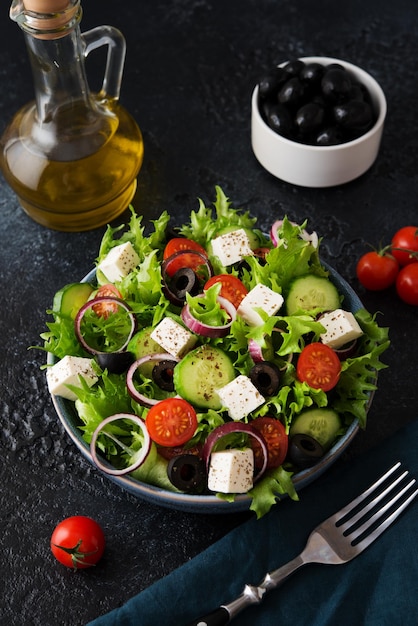 Ensalada griega con tomates, pepinos, aceitunas y queso feta en un plato sobre un fondo de hormigón, cocina típica griega