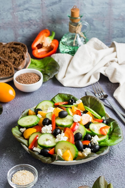 Ensalada griega de tomates pepinos pimientos aceitunas lechuga y queso en un plato Vista vertical