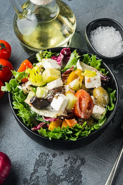 Ensalada griega tradicional con verduras frescas, queso feta y aceitunas, en mesa gris, vista superior plana
